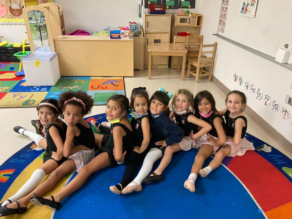 Group of ballerinas posing together on classroom rug